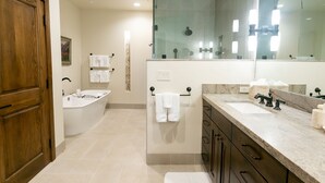 A modern bathroom with a bathtub, a large mirror, and a vanity with a sink and countertop. - Luxury One Bedroom with Mountain View 1 Apartment Hotel by RedAwning (Park City)