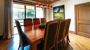 A dining area with a wooden table and chairs, a chandelier, and a painting on the wall. - Luxury One Bedroom Corner Suite 1 Apartment Hotel by RedAwning (Park City)
