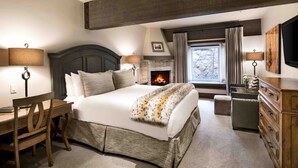 Une chambre à coucher avec un grand lit, un bureau en bois, une commode et une cheminée.
