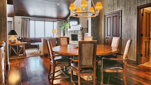 A spacious dining area with a wooden table and chairs, a chandelier, and a stone fireplace.