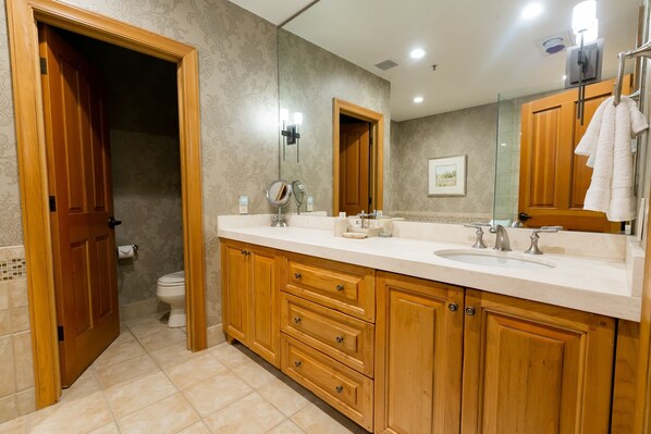 A bathroom with wooden cabinets, a double sink, and a large mirror.