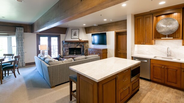 A modern kitchen with wooden cabinets, a central island, and a stone fireplace.