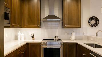 A kitchen with wooden cabinets, a stainless steel range hood, a built-in oven, a microwave, and a sink.