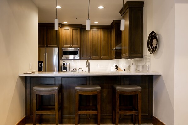 Una cocina moderna con armarios de madera, electrodomésticos de acero inoxidable y una encimera blanca.