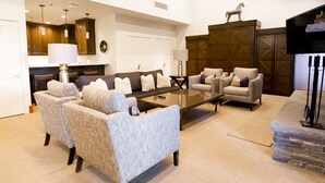 A spacious living room with a large sofa set, a coffee table, and a fireplace. There are wooden cabinets and a television mounted on the wall. - Luxury Four Bedroom Multi-Level Townhouse with Hot Tub 4 Townhouse by RedAwning (Park City)