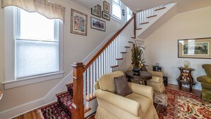 A living room with a staircase, a sofa, a coffee table, and a rug. - Beachfront Home with Sunset Views, Steps to Bay (Cape Charles)