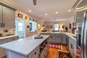A modern kitchen with a central island, built-in appliances, and a view to the dining area.