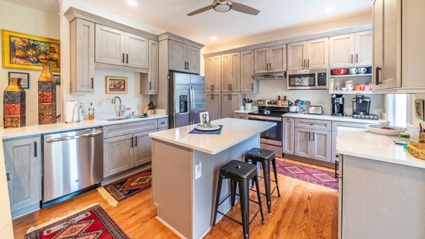 A modern kitchen with grey cabinets, stainless steel appliances, and a central island with stools. - Beachfront Home with Sunset Views, Steps to Bay (Cape Charles)