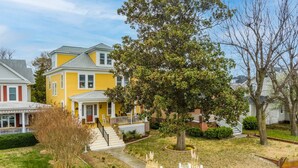 A yellow house with a front porch and a tree in the yard. - Beachfront Home with Sunset Views, Steps to Bay (Cape Charles)