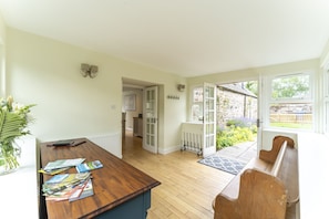 Relax in this open-plan living area with a dining table and bench, offering a serene view of the garden through the large window.