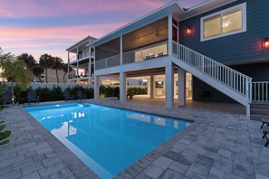Una casa de dues plantes amb piscina, un porxo cobert i una escala que condueix al pis superior.