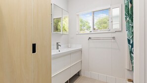 A bathroom with a white vanity, a mirror, a window, and a towel rack. - Yellow House Gracetown ~ A Peaceful Beach house with Ocean Views (Gracetown)