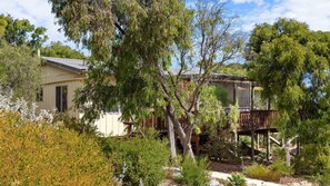 A house with a deck, surrounded by various trees and shrubs. - Yellow House Gracetown ~ A Peaceful Beach house with Ocean Views (Gracetown)