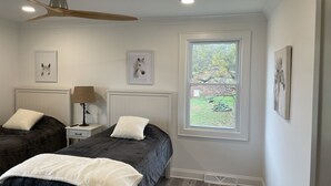 A bedroom with two beds, a ceiling fan, a window with a view of the outdoors, and framed artwork on the walls. - Travelers Rest, Furman, Greenville, and a mountain view! (Travelers Rest)