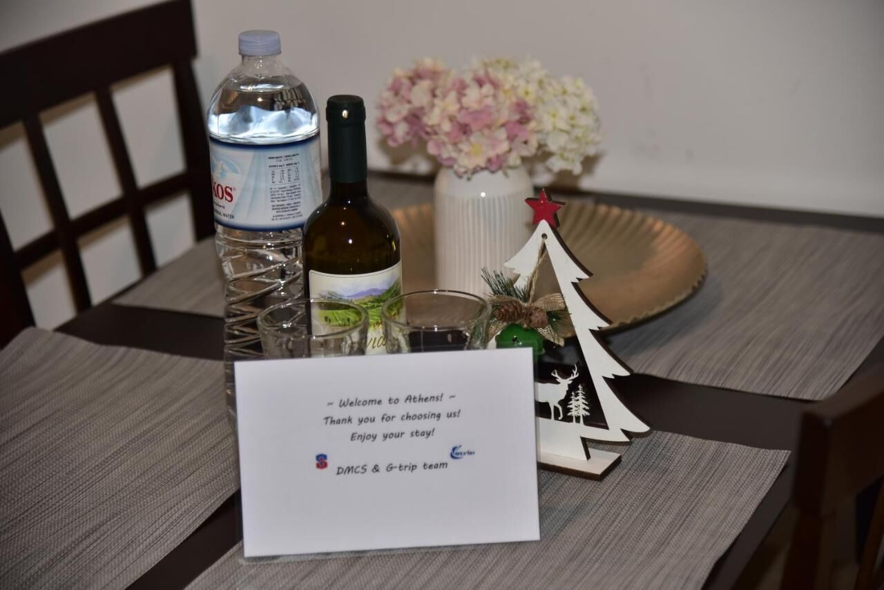 A table with a water bottle, a wine bottle, a glass, a small Christmas tree, and a welcome sign.