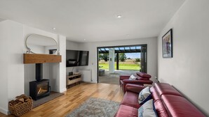 A modern living room with a fireplace, a red leather sofa, and a television.