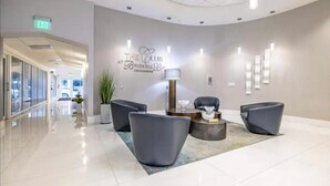 A modern hotel lobby with a curved ceiling, a reception desk, and seating area. - Skyline City Views | Pool, Hot Tub & Fitness Room! (Miami)