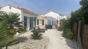 A courtyard with a patio area, outdoor seating, and a stone building. - Family home for up to 10 people, 15 min walk from the beach (Dolus-d'Oléron)