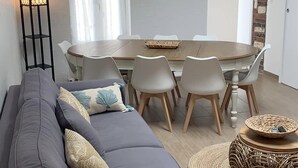 A modern living room with a grey sofa, a round dining table with six chairs, and a decorative mirror on the wall. - Family home for up to 10 people, 15 min walk from the beach (Dolus-d'Oléron)