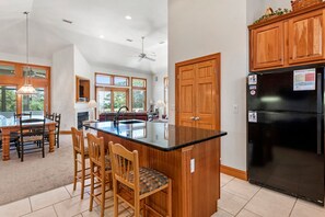 A kitchen with wooden cabinets, a black refrigerator, and a central island with bar stools.