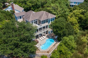 A large house with a swimming pool surrounded by trees.