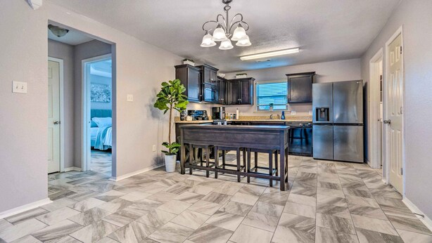 A modern kitchen with dark cabinets, a central island, and a stainless steel refrigerator. - 8 Mi to Downtown Little Rock: Home w/ Fenced Yard (Little Rock)
