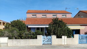 A two-story building with a tiled roof, a gated entrance, and a gravel driveway.
