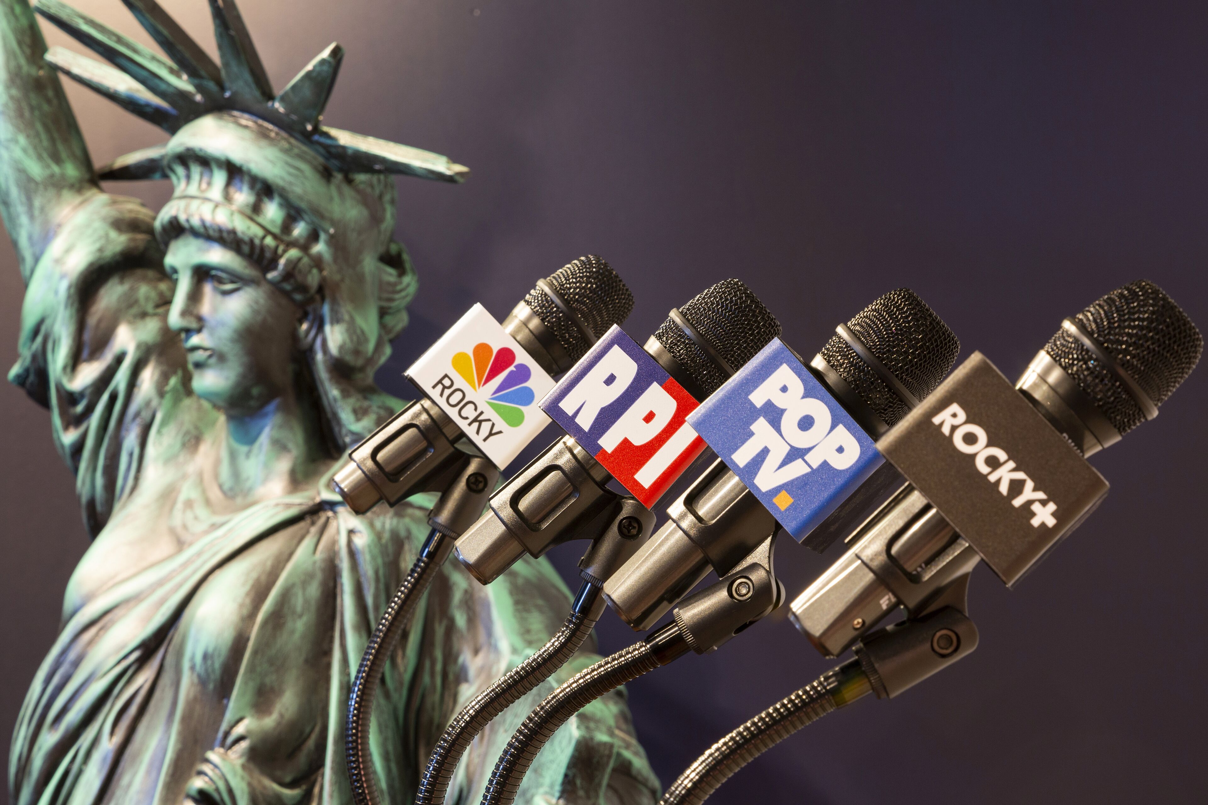 A statue with microphones attached to it, each labeled with different logos.