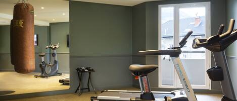 A gym with a punching bag, treadmills, and dumbbells.
