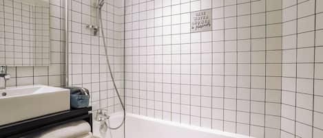 Un baño moderno con una bañera blanca, una ducha con cerramiento de vidrio y un mueble de tocador negro con lavamanos y toallas.