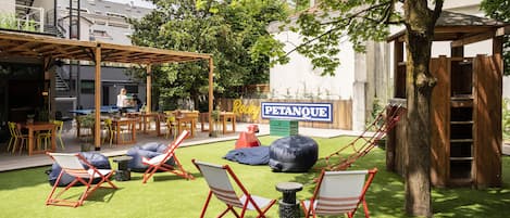 Un espacio de estar al aire libre con sillas rojas y blancas, una pérgola de madera y un letrero que dice "Pétanque".