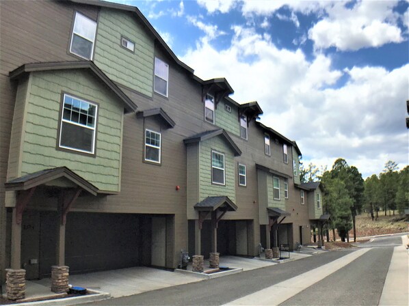 A row of townhouses with attached garages, a paved driveway, and a clear sky. - CΛsitΛ ΛrizonΛ - Flagstaff - Designed for LARGE FAMILIES + Kids (Flagstaff)
