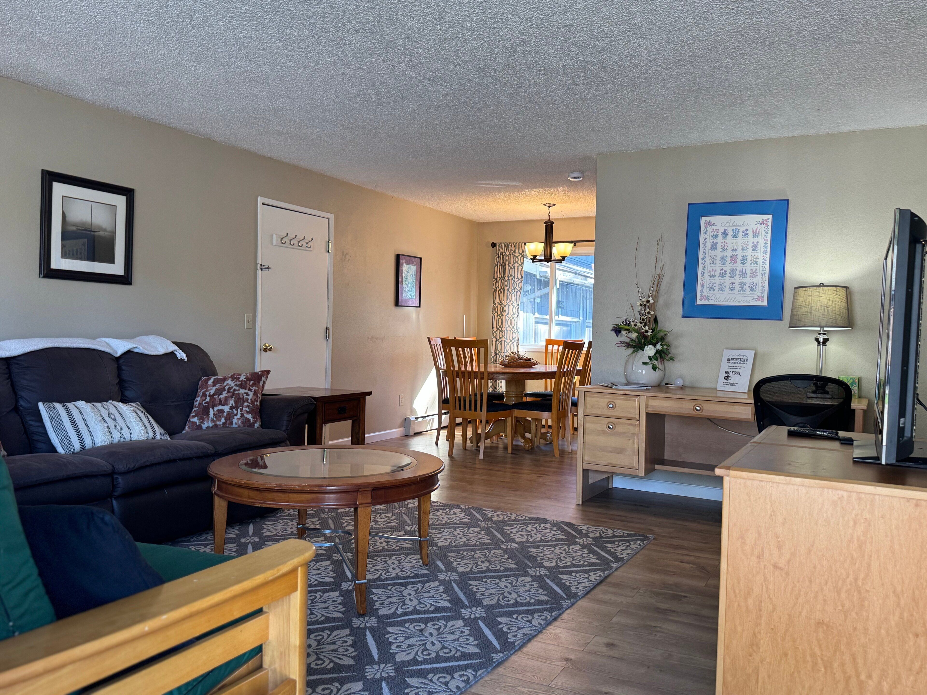A living room with a sofa, coffee table, and dining area with chairs and a table.