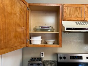 A kitchen with wooden cabinets, a glass baking dish, white bowls, a toaster, and a stove.