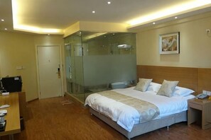A hotel room with a bed, bedside table, and a glass-enclosed shower area. - Zhongjiang ikea business hotel (Zhongjiang)