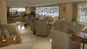 Un vestíbulo de hotel con varias zonas de estar, amplias ventanas y un diseño moderno y limpio.