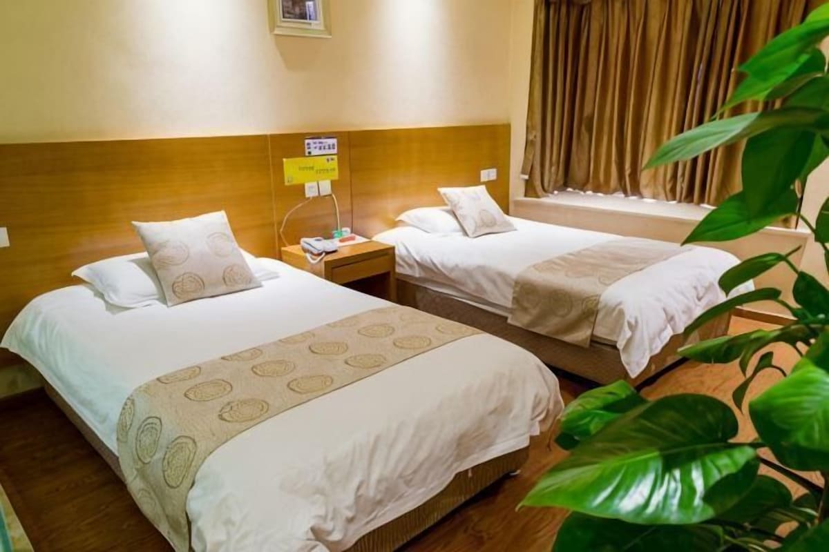 Habitación de hotel con dos camas, una mesita de noche con teléfono y una ventana con cortinas.