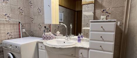 Un baño con lavadora, lavamanos y espejo con iluminación.