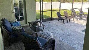 A covered patio with wicker furniture, a ceiling fan, and a view of a backyard. - Gone Coastal! Large heated pool home 30 min from beaches (North Port)