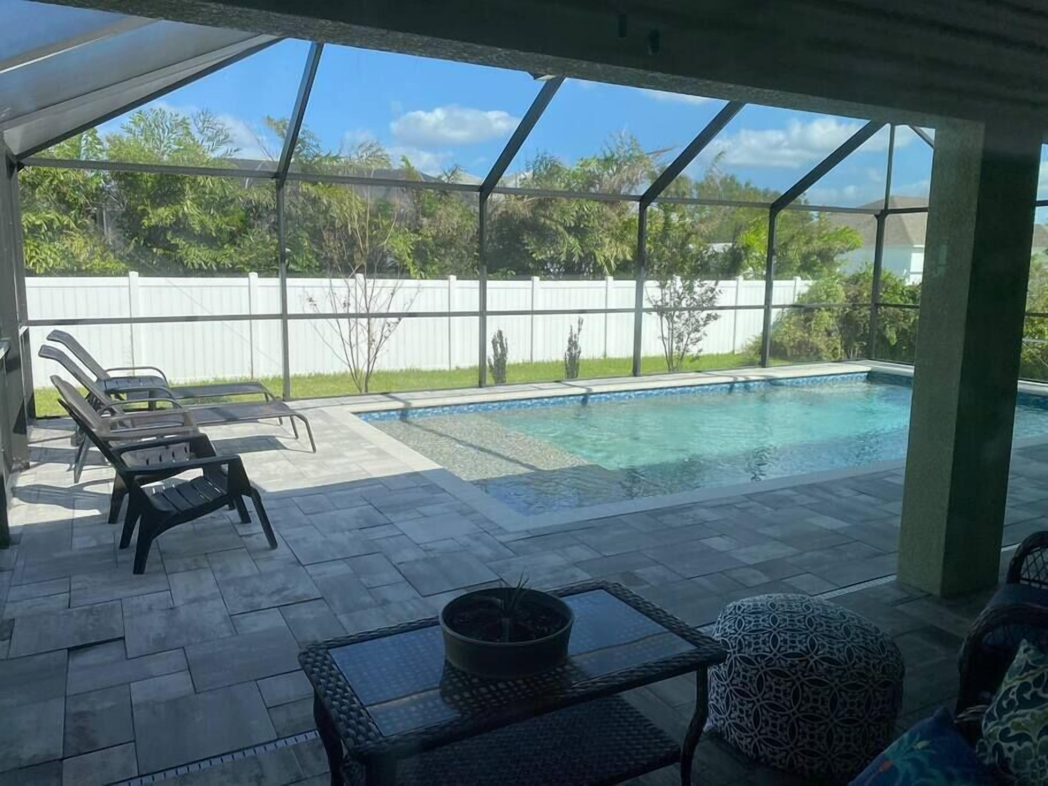 Un espace extérieur abrité comprenant une piscine, des chaises longues et une table.
