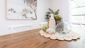 Une table à manger avec un plateau en bois, un pichet en verre et un set de table en crochet.