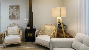 Un salon avec deux fauteuils en osier, un canapé, une lampe et une cheminée.