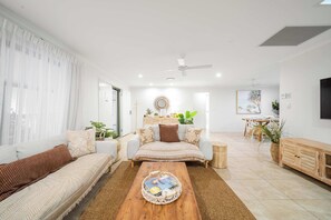 A modern living room with a sofa, coffee table, and a dining area with a table and chairs.