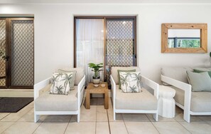 A living room with two white sofas, a small wooden table, and a potted plant.
