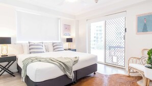 A modern bedroom with a large bed, a wooden floor, a balcony with a view, and a wall-mounted artwork. - Kings Beach Coast & Glasshouse Views 3BD Apartment (Kings Beach)