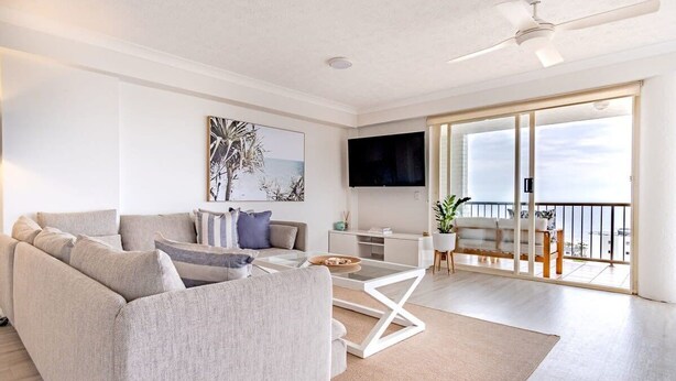 A modern living room with a sofa, coffee table, and a flat-screen TV. - Kings Beach Coast & Glasshouse Views 3BD Apartment (Kings Beach)