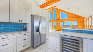 A modern kitchen with white cabinets, a stainless steel refrigerator, and a blue tiled backsplash.