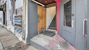 A building entrance with a wooden door, a metal handrail, and a staircase leading inside. - Modern Yankton Apartment Near Riverside Park! (Yankton)