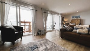 Ein geräumiges Wohnzimmer mit großem Fenster, einem Sofa, einem Couchtisch und einem Teppich.