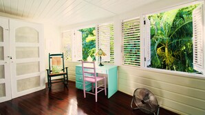 A room with a desk, a chair, a fan, and a view of lush greenery through open shutters. - Hummingbird Villa - Tropical 3 bedroom Villa with Panoramic Views (Cap Estate)
